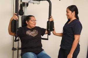 Persona adulta en consulta de fisioterapia con profesional