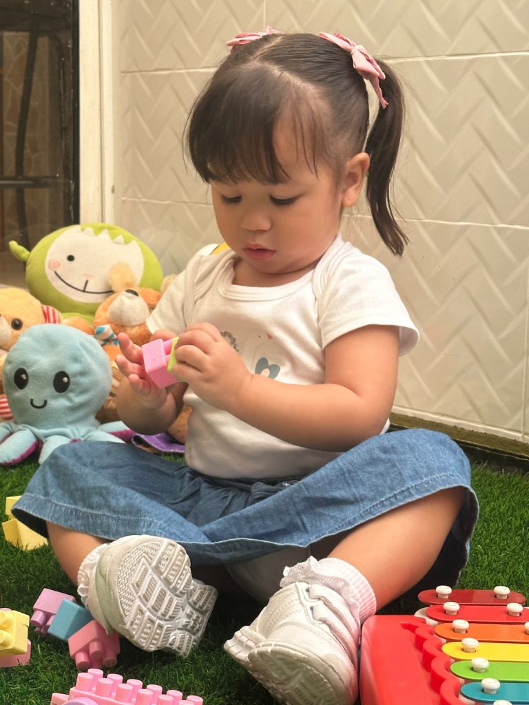Niña realizando ejercicios de motricidad fina sobre grama artificial