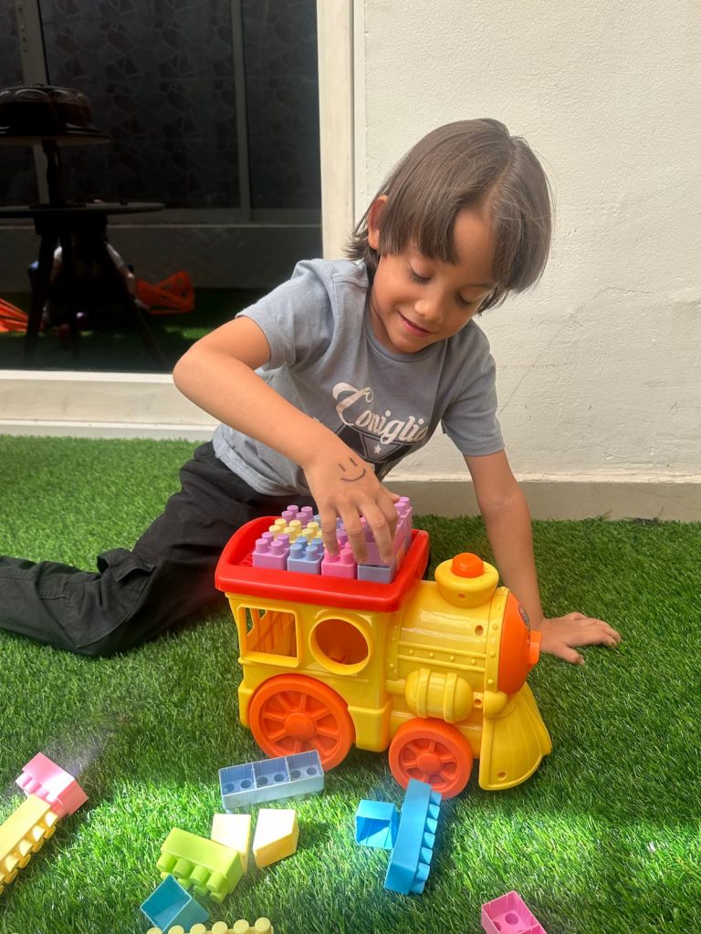 Niño realizando ejercicios de motricidad fina sobre grama artificial